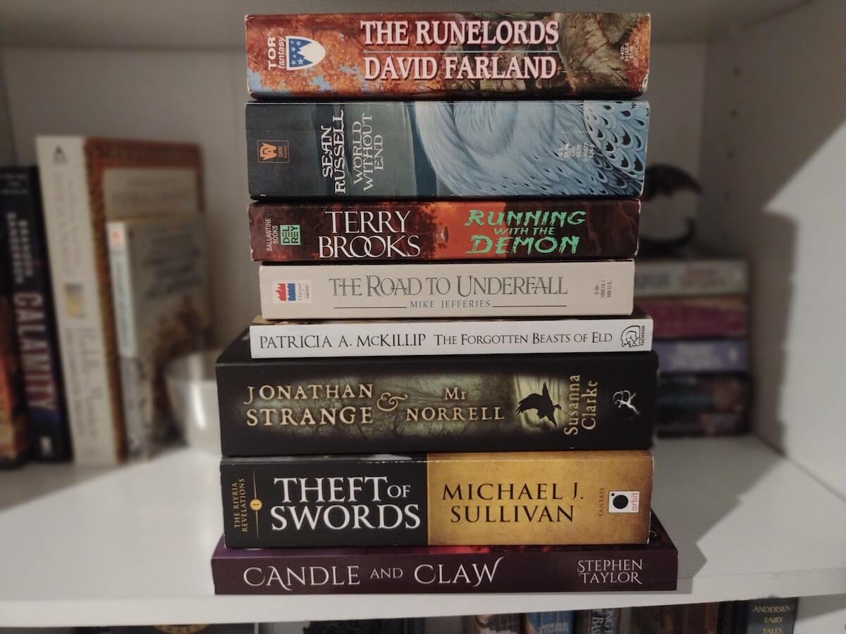 Fantasy to read; a stack of books including works by Sean Russell, Susanna Clarke, and Stephen Taylor.