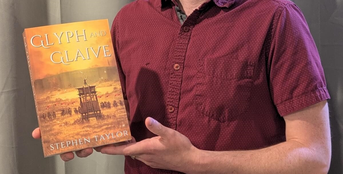 Author Stephen Taylor holding his epic fantasy book Glyph and Glaive